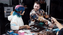 a man and a woman sit at a table with a sign that says black lives matter in the background