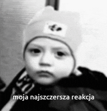 a black and white photo of a baby wearing a hat with the caption moja najszczersza reakcja