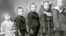 a group of children are posing for a picture and one of them is wearing a plaid dress