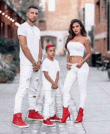 a man and a woman standing next to each other with a boy wearing red hair