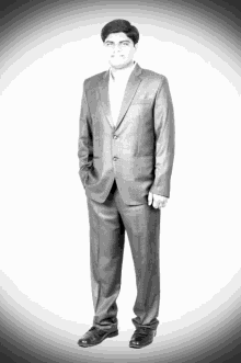 a man in a suit with his hands in his pockets stands in front of a white background