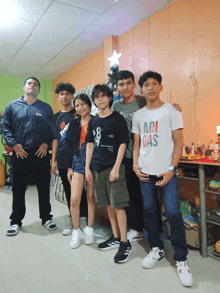 a group of young people posing for a picture with one wearing a adi das shirt