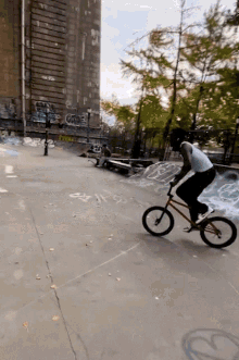 a person riding a bike in a skate park with graffiti on the wall including one that says ' a ' on it