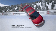 a red nissan sentra is driving through the snow