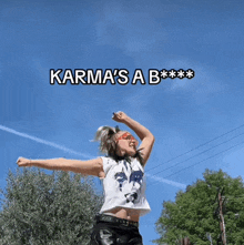 a woman with her arms outstretched and the words karma 's a b *** on the bottom