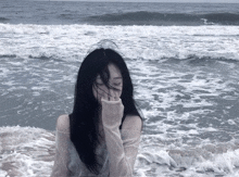 a woman covering her face in the ocean