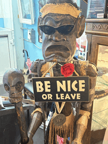 a statue has a sign that says be nice or leave on it