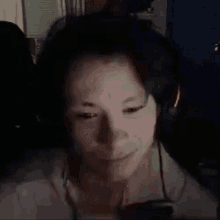 a close up of a person wearing headphones and smiling in the dark .