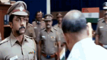 a police officer is talking to a man in a white shirt in front of a group of police officers .