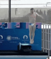 a man is jumping off a diving board in front of a sign that says " metropole grand paris "