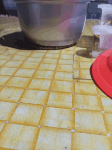 a bowl sits on a yellow tile floor next to a red lid