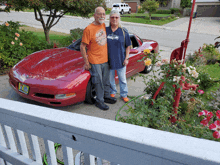 a man and woman standing next to a red sports car