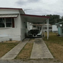 a bugatti is parked under a carport in front of a house