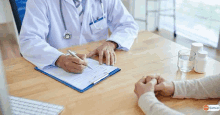 a doctor is sitting at a desk talking to a patient .