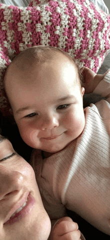 a woman holds a baby in her arms and the baby is smiling