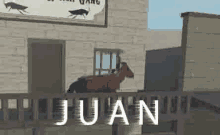 a goat is standing on a railing in front of a building with the word juan written on it .