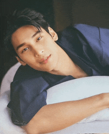 a young man laying on a bed with his head on a pillow