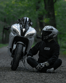 a person wearing a helmet with the number 92 on it sits in front of a motorcycle