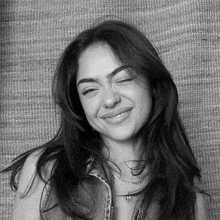 a black and white photo of a woman wearing a denim vest and a necklace .