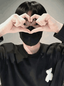 a person wearing a mask making a heart shape with their hands