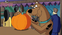 scooby doo is holding a pumpkin in his mouth in a cartoon scene .