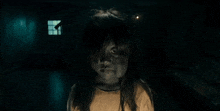 a little girl with long hair is standing in a dark room .