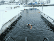 a person is swimming in a body of water with a building in the background that says ' nordic '