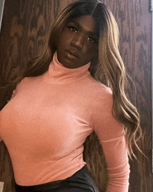 a woman wearing a pink turtleneck and black skirt