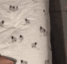 a white blanket with sheep on it is laying on a bed