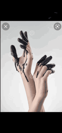 a woman 's hands are covered in black paint and are reaching up