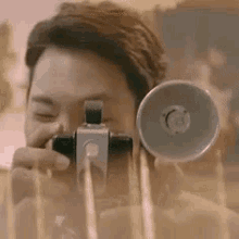 a man is taking a picture with a camera and looking through it .