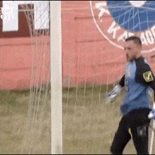 a soccer goalie is standing in front of a goal with a sign in the background that says ' a ' on it