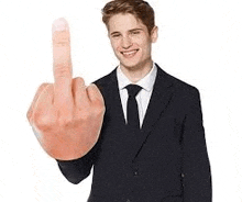 a young man in a suit and tie is holding a middle finger .