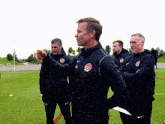 a group of men are standing on a field and one of them is wearing a jacket that says canada on it