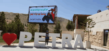 a woman is standing in front of a large petra sign