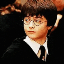 harry potter is wearing glasses and a tie in a close up of his face .