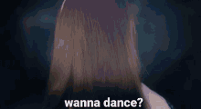 a woman is dancing in a dark room with the words `` wanna dance '' written in the foreground .