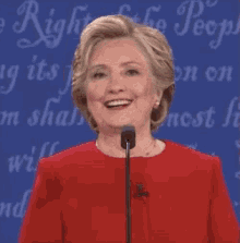 a woman in a red dress is smiling in front of a sign that says ' freedom of the people '