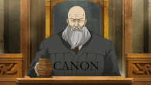 a bald man with a beard is sitting in a judge 's chair with canon written on his shirt