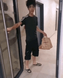 a young man is standing in a hallway holding a bag that says ' point ' on it .