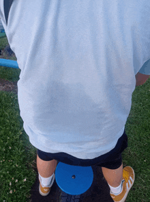 a person wearing a white shirt and yellow adidas shoes is standing on a blue stool