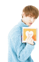 a young man in a blue sweater is holding a card with a heart in it