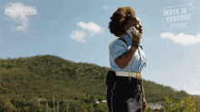 a woman in a police uniform is talking on a cell phone in front of a sign that says britbox