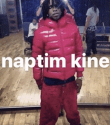 a man in a red jacket is standing in front of a mirror with the words naptim kine written on it