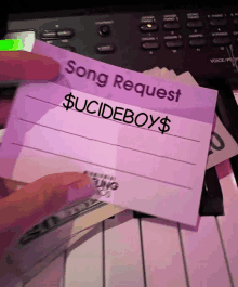 a person is holding a purple card that says song request $ suicideboys