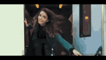 a woman is getting out of a bus with her arms outstretched and smiling .