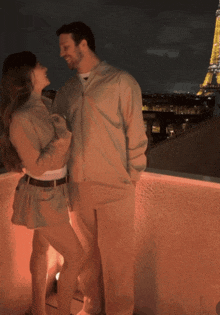 a man and a woman are standing next to each other in front of the eiffel tower