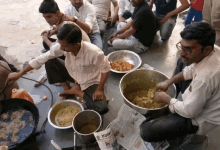 a group of men are preparing food with a newspaper on the ground that says ' india ' on it