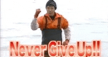 a man in a wet suit is giving a fist pump in front of a sign that says `` never give up ! ''