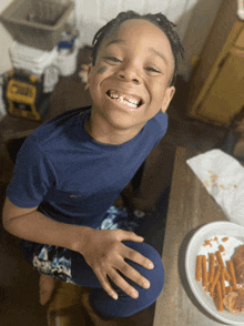 a young boy sitting at a table with a plate of carrots on it